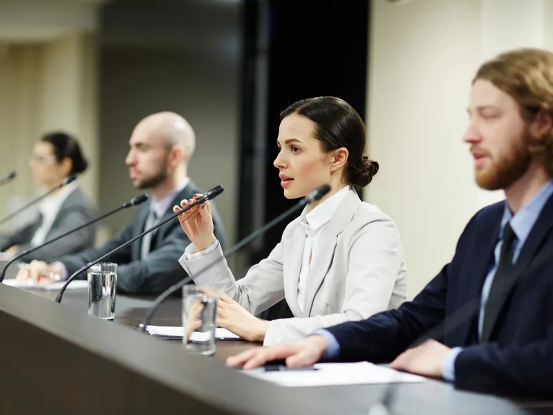 Eine der Rednerinnen, die mit micrpophone unter ihren Kollegen auf einer Konferenz oder einem politischen Forum spricht