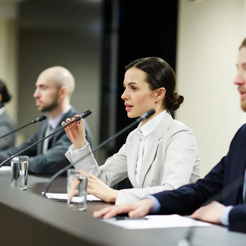 Eine der Rednerinnen, die mit micrpophone unter ihren Kollegen auf einer Konferenz oder einem politischen Forum spricht